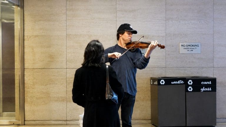 A violinist playing in a subway station while busy commuters pass by, inspired by the Joshua Bell experiment on perception and attention